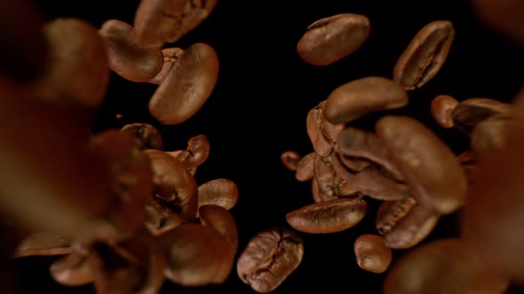 Super Slow Motion Detail Shot of Coffee Beans Falling Down on Black Background at 1000Fps alt