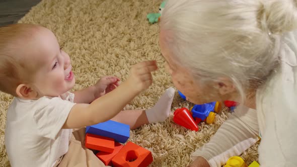 Lovely Baby Boy Enjoying Playing with Grandma at Home