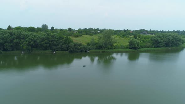Aerial View Fisherman is Fishing Sitting on an Inflatable Boat in Lake alt