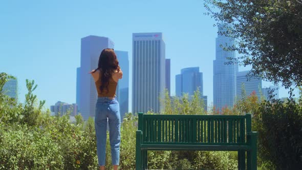 Unknown Woman Standing in Park Making Photo Skyscrapers on Smartphone Back View alt