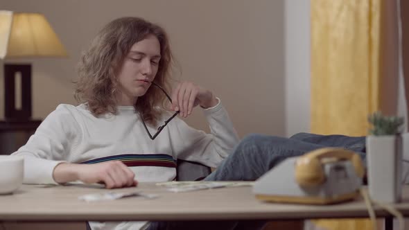 Relaxed Retro Geek with Feet on Table Admiring Dollars and Thinking alt