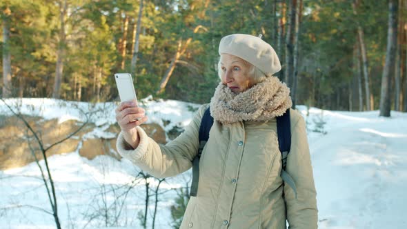 Beautiful Senior Woman Hiker Taking Pictures with Smartphone Camera in Winter Park alt