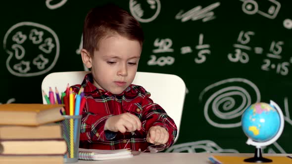 Cute child boy doing homework. Clever kid drawing at desk. Schoolboy. alt