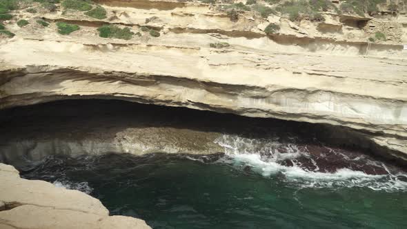 Mediterranean Sea Waves Rushes Back and Forth in St Peters Pool Stone Beach Cave