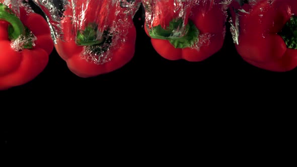 Super Slow Motion Red Sweet Peppers Fall Under the Water with Air Bubbles alt