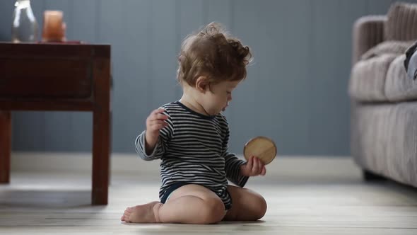 baby play with piece of wood on a floor