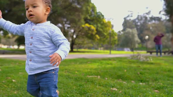 Mixed-race Boy Walking on Grass, Waving Hand, Saying Something alt