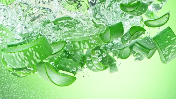 Super Slow Motion Shot of Aloe Vera Cuts Falling Into Water on Green Background at 1000Fps alt