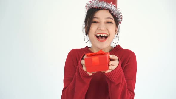 happy young woman with hat and holding a red christmas gift box in a gesture of giving