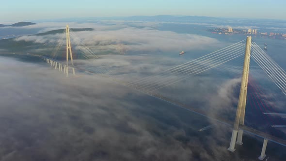 The Pylons of the Giant Cablestayed Bridge Rise Above the Seaside Morning Fog alt