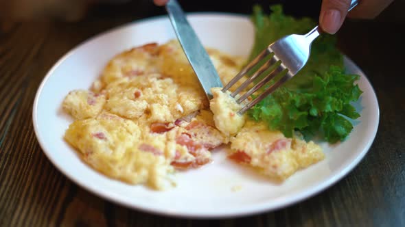Woman Eating Omelette on a Plate with Greens