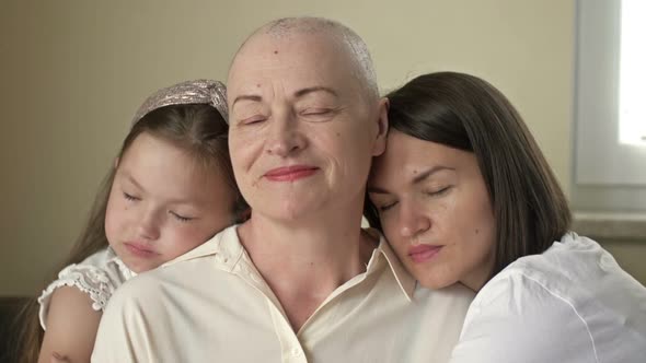 An Adult Daughter and Little Granddaughter Hug a Sad Elderly Woman Who Has Gone Bald After alt