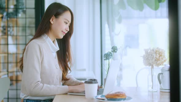 young attractive asian female wear casual cloth hand use smartphone and laptop alt