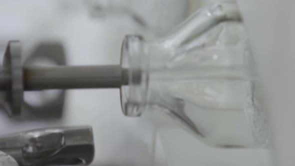 Vertical Video Glass Bottles on a Medical Solution Conveyor at Filling Station Close Up Selective