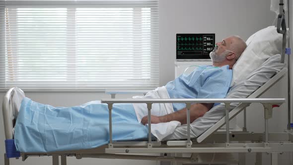 Senior Male Patient Lying in a Hospital Bed Wearing Oxygen Mask alt