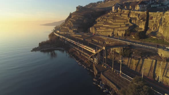 Train Goes Along Lake Geneva Shore at Sunset. Vineyards and Houses. Aerial View alt