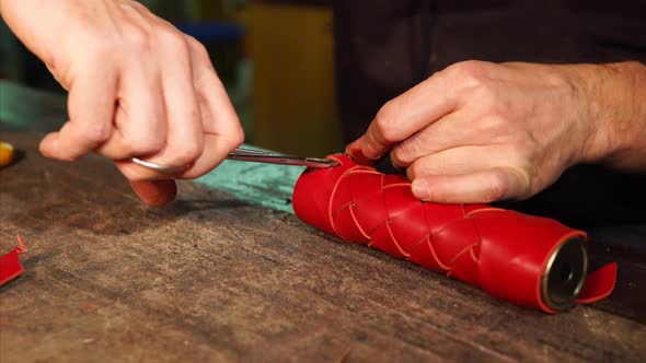 Master Is Fixing Edge of Leather Strip on a Red Casing for Kaleidoscope Tube alt