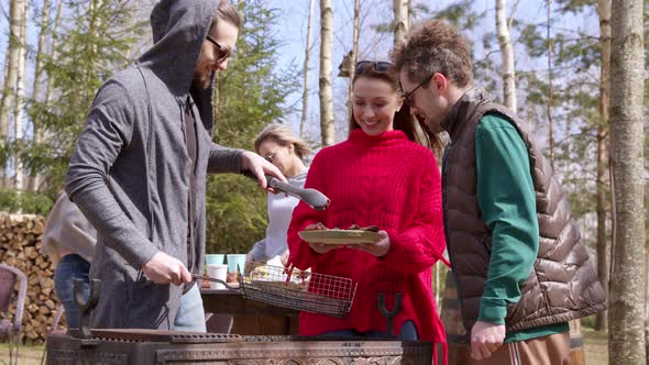 Friends Make Barbecue on Summer Picnic, Handsome Guy Puts Grilled Meat on Plate