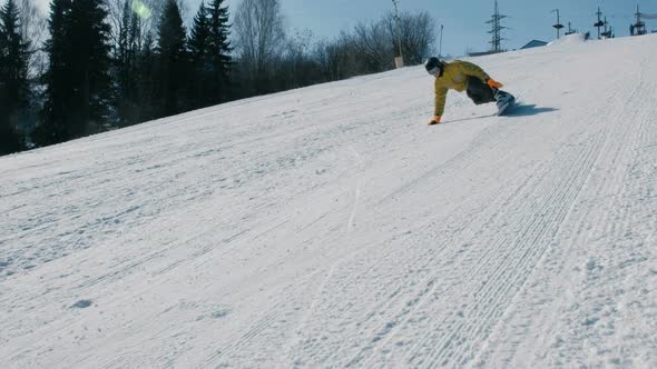 Man Goes Down the Mountain on a Snowboard Slope Next To the Lift.