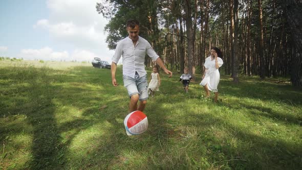 Happy family playing a soccer in the park. Funny kids playing ball. Slow motion. alt