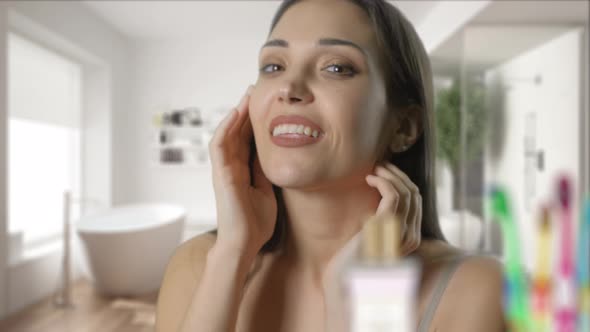 Happy Young Woman Is Smiling Checking Her Face in Bathroom Mirror at Home. The Pretty Girl Is alt