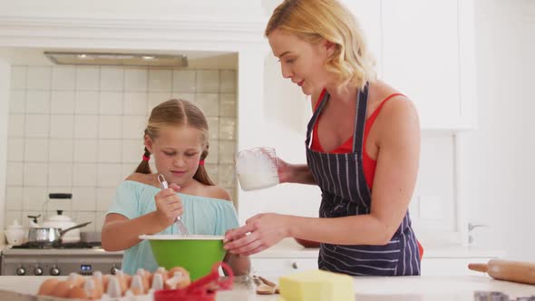 Caucasian mother and daughter baking together in the kitchen at home alt