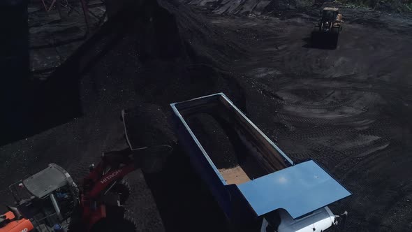 The Drone Flies Around with a Heavy Dump Truck Into Which the Loader Fills Coal
