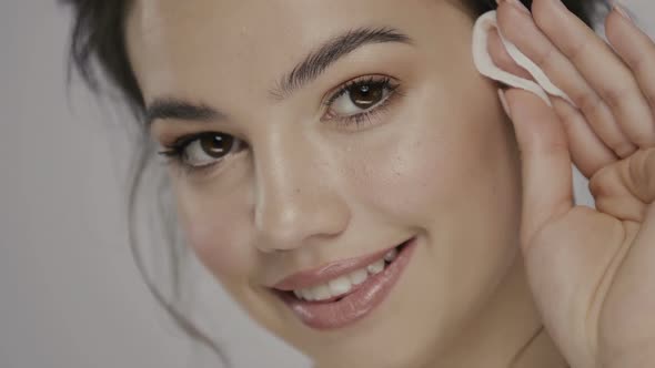 Pretty Girl Touching Her Eyebrow with White Sponge and Looking To Camera alt