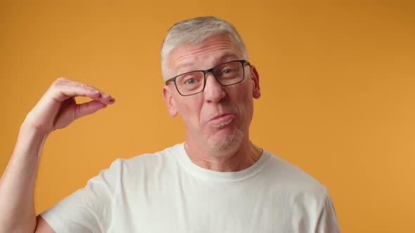 Senior Man in Glasses Doing Bla Bla Gesture Against Yellow Background