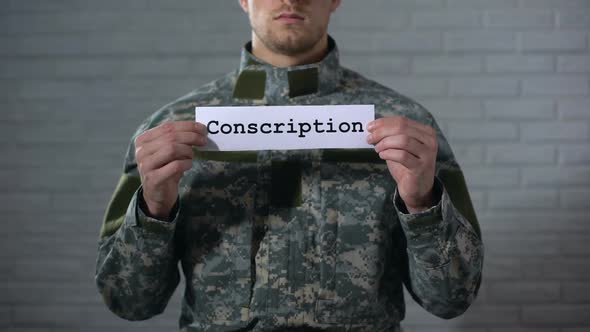 Conscription Word Written on Sign in Male Soldier Hands, Military Service, Duty alt