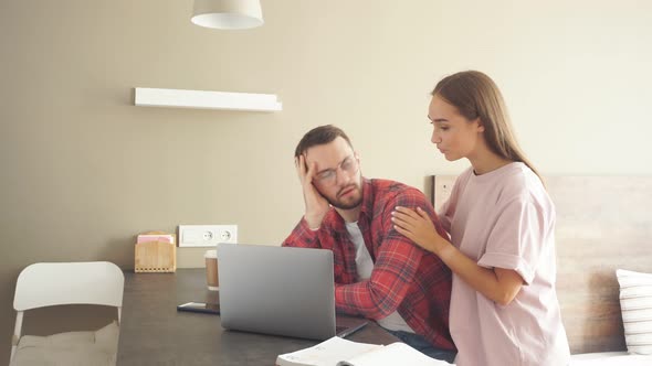 Upset Male Sits at Black Wooden Table Stares at Computer with Dissatisfied Feeling alt