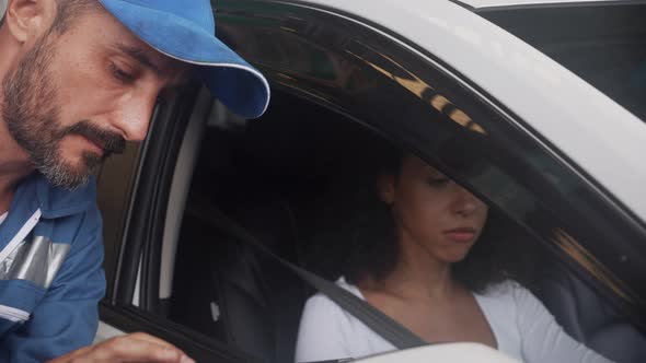 Customer young woman talking with mechanic man about problems of engine car and giving key car.