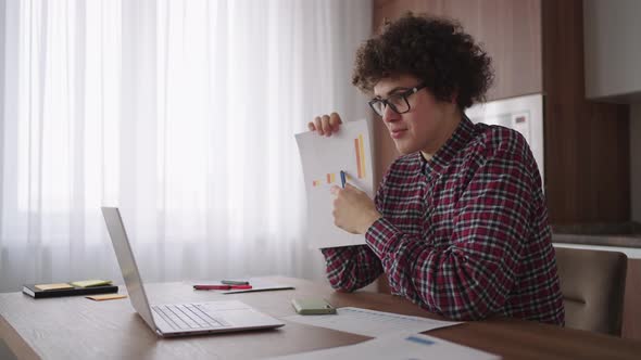 Curly Haired with Glasses Business Man Sitting at Office From Home Desk Looking at Camera and alt