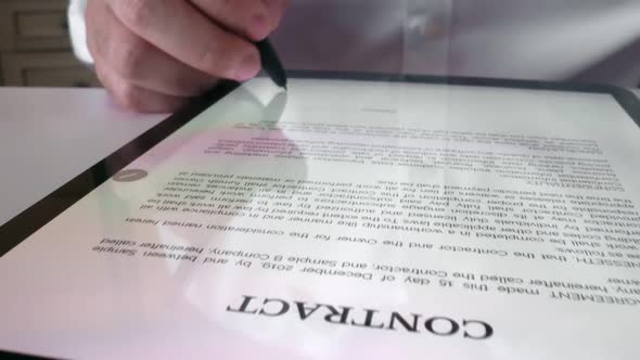 Man sign signature on digital contract at tablet computer in close up view. alt