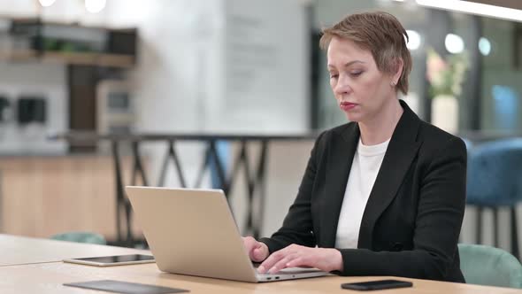 Stressed Businesswoman with Laptop Having Headache in Office alt