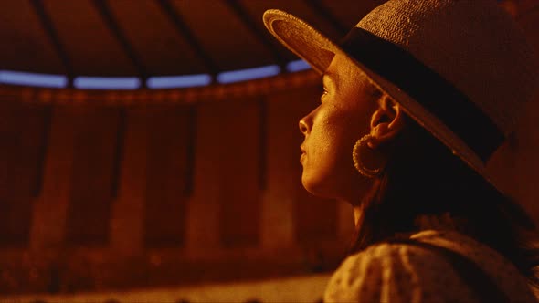 A young girl in a hat looking at the eternal flame in the evening on Mamayev Kurgan alt