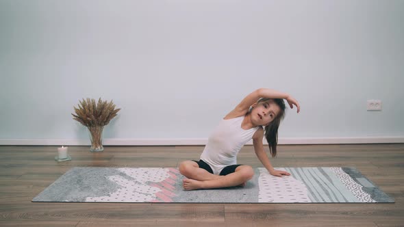 Caucasian Girl Does The Child Sitting on the Mat Makes Bends to the Sides Gymnastic Exercises Online