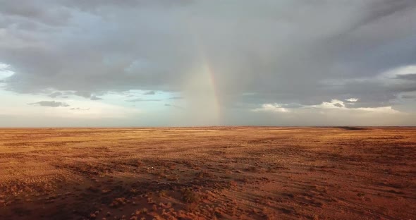 Drone shot of a rainbow in the distance on a very dry Namibian sheep farm. Drone moving forward with alt