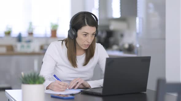 Woman taking notes while talking on video call