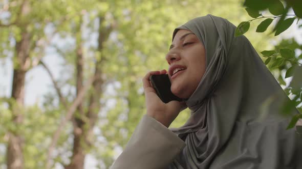 Muslim Woman Having Phone Call in Park alt