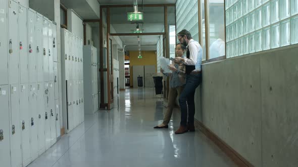 Colleagues discussing over digital tablet in corridor 4k alt