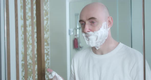 Middleaged is Shaving Using Disposable Razor in Bathroom Closeup Side View alt