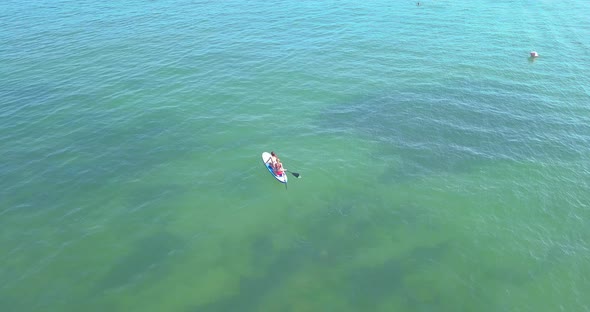 Two Girls are Floating in the Sea on a SUP Board