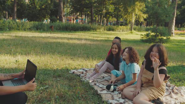 School Teacher Using Laptop Showing Study Material to Pupils Outdoors alt