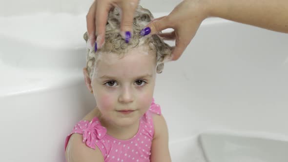 Cute Blonde Girl Takes a Bath in Swimwear. Little Child Washes Her Head alt