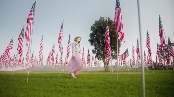 Young Woman Walking Between Flagpoles on Summer Day Independence or Labor Day alt
