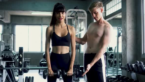 Sportswoman Practicing Front Lateral Raise Exercise with Her Trainer at the Gym alt
