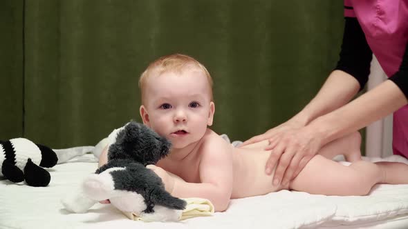 The masseuse gives a back and buttocks massage to baby (boy) 09, Stock Footage