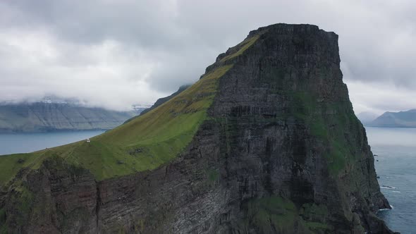 Flight Away From a Huge Cliff with a Small Lighthouse on Kalsoy, Faroe Islands alt
