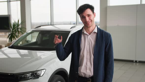 Portrait of Joyful Man with Keys to a New Car in His Hands Smiling and Looking at Camera Pointing